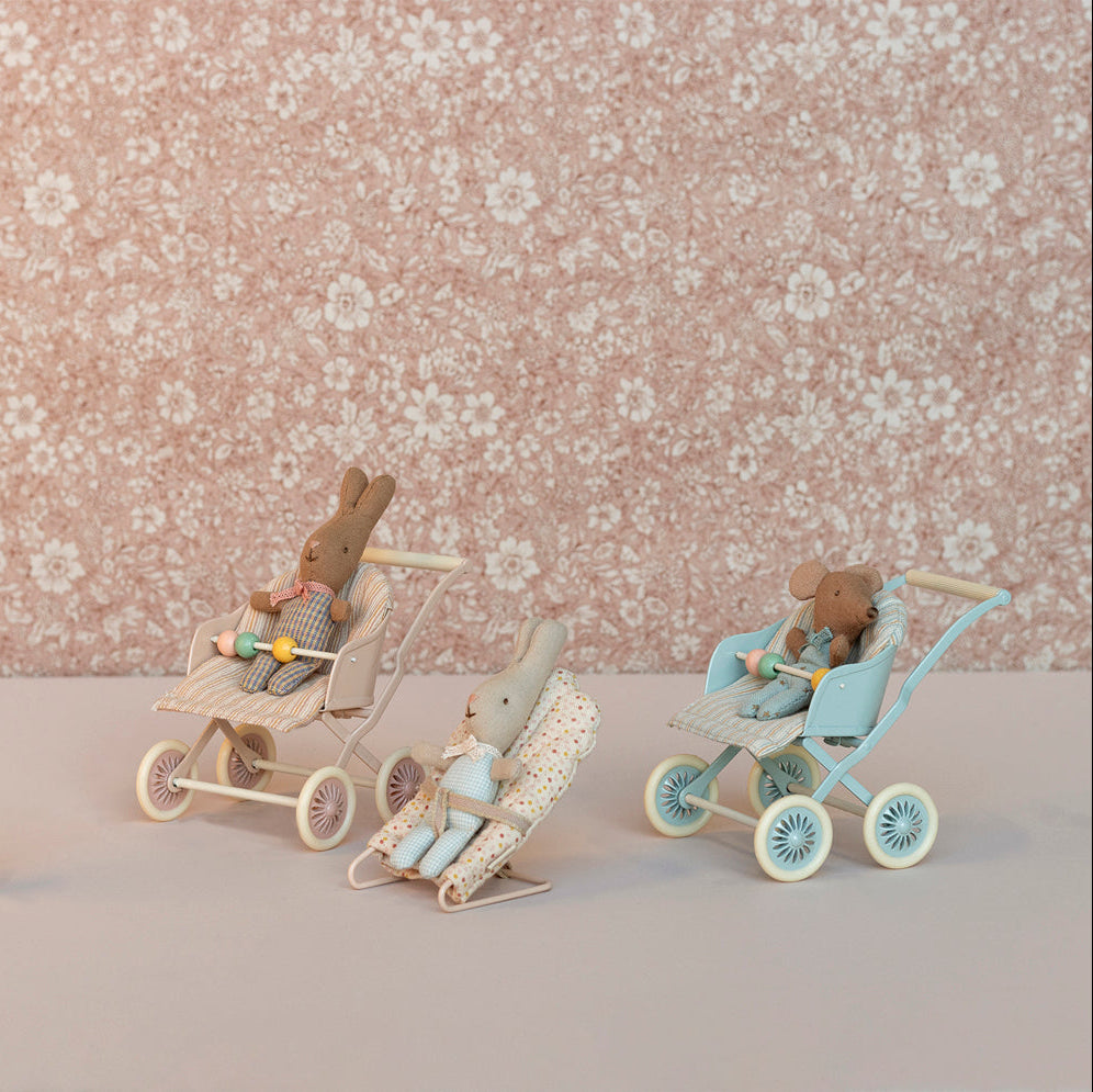 Miniature toy figures with strollers against a floral-patterned background