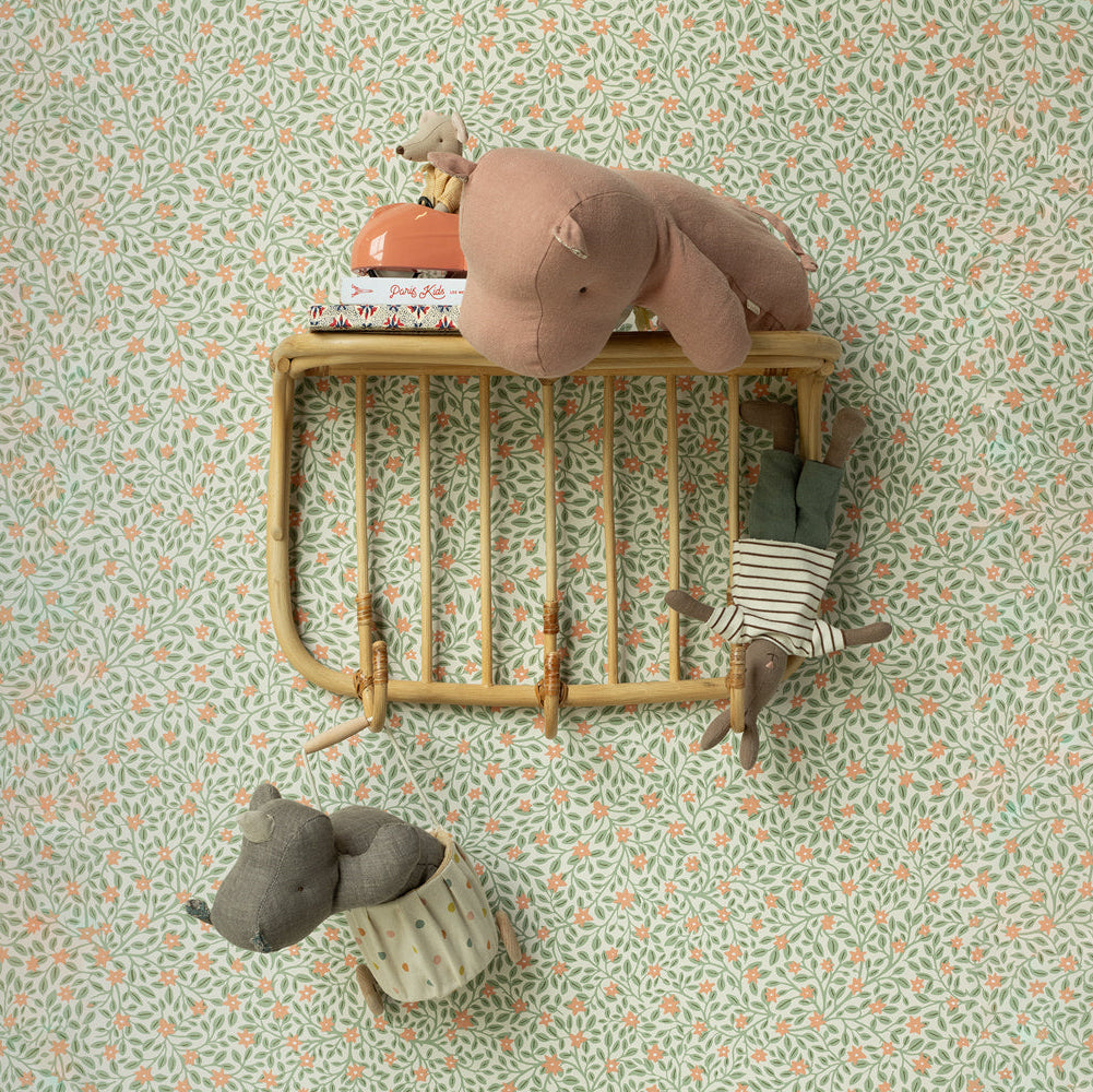 Small wooden bed with plush toys on a patterned wall