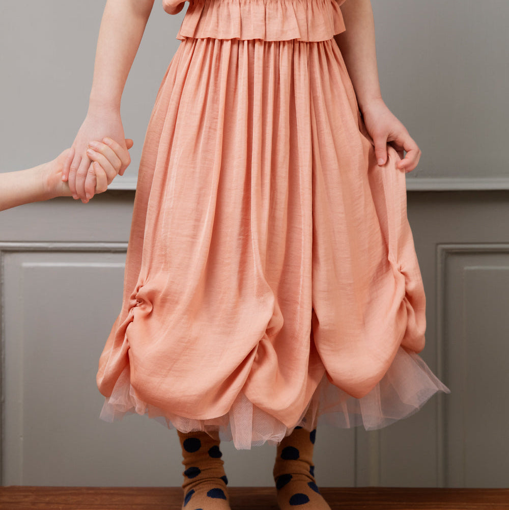 Person wearing a peach dress with a plain background