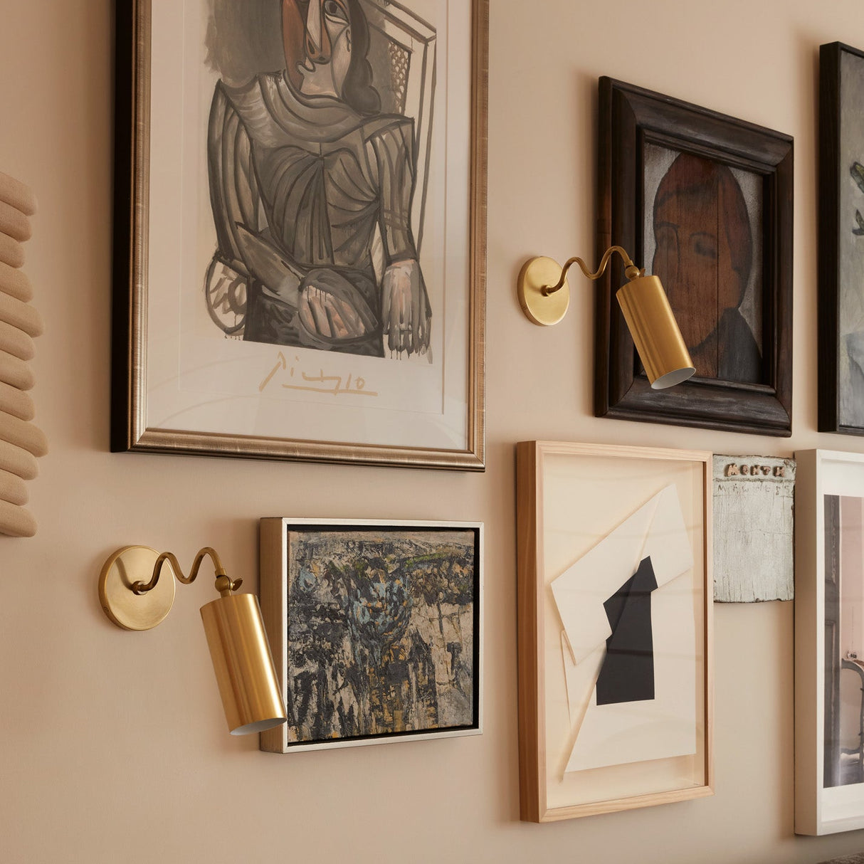 Wall with framed artwork and gold sconces in a living room setting