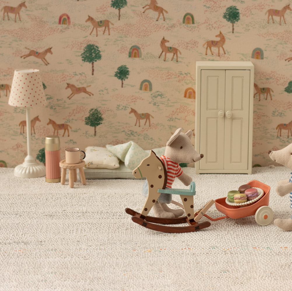Children's room with toys and a patterned wall featuring animals and trees.
