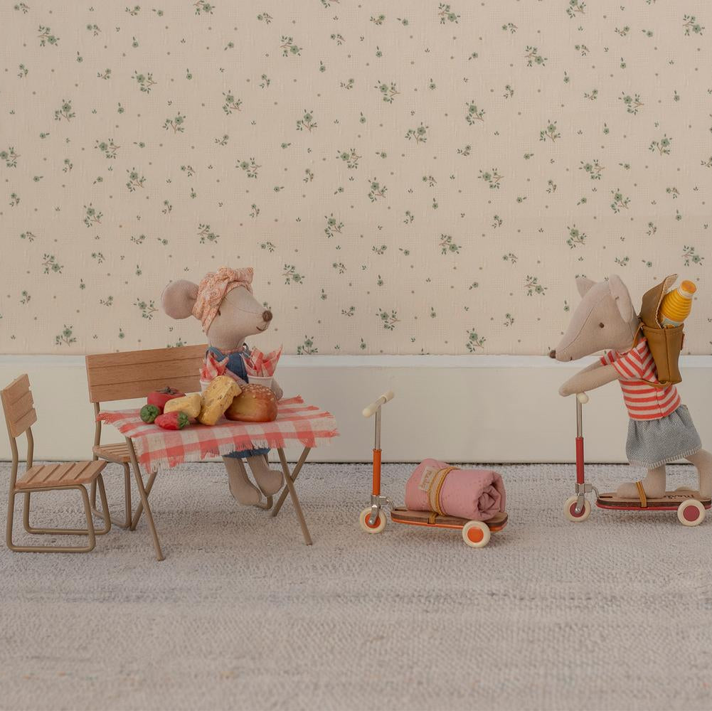 Two toy mice with a small table and chairs on a patterned floor.