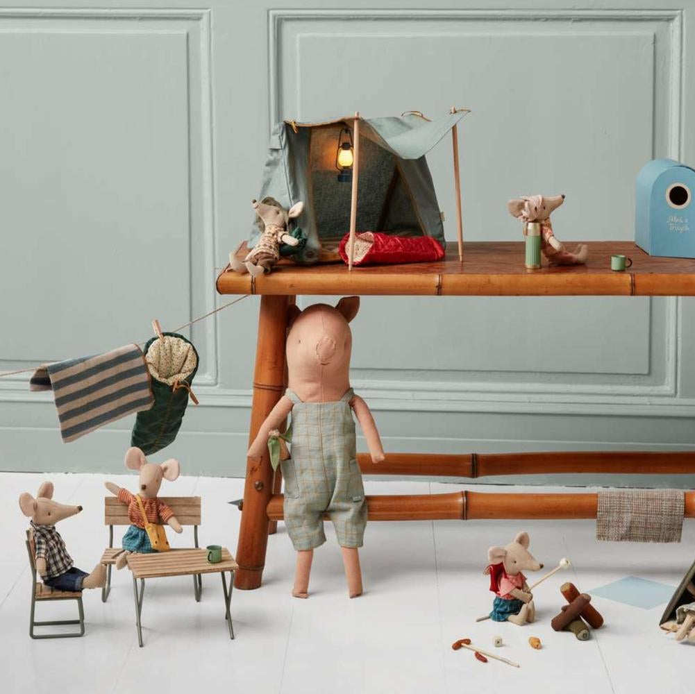 Miniature diorama with toy figures and accessories on a wooden table against a gray wall.
