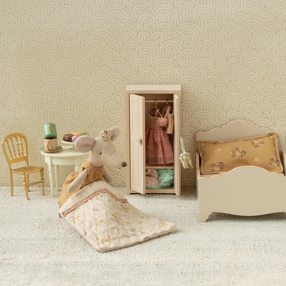 Miniature bedroom set with bed, wardrobe, chair, and mouse figure on a textured surface.