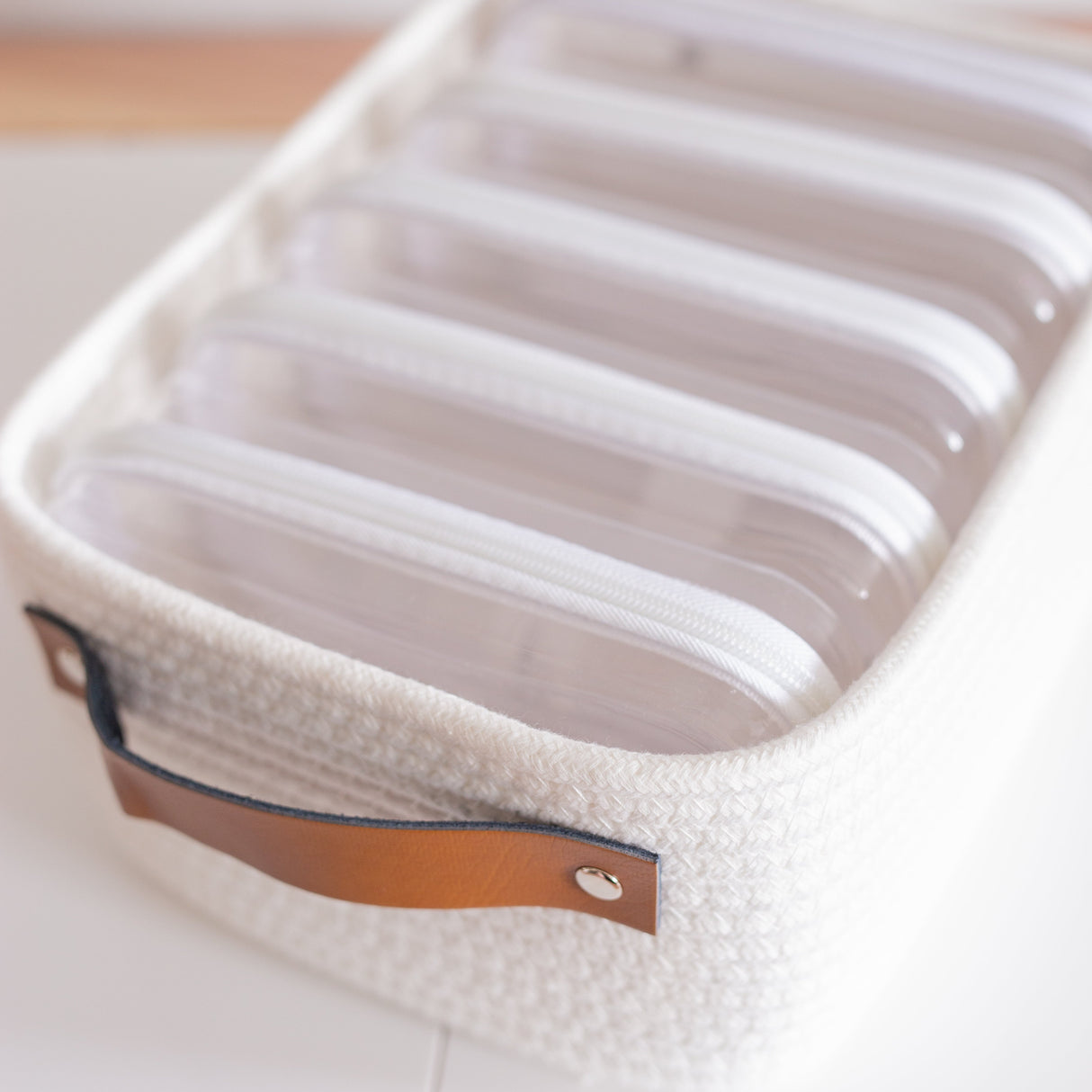 White woven basket with leather handle on a light background