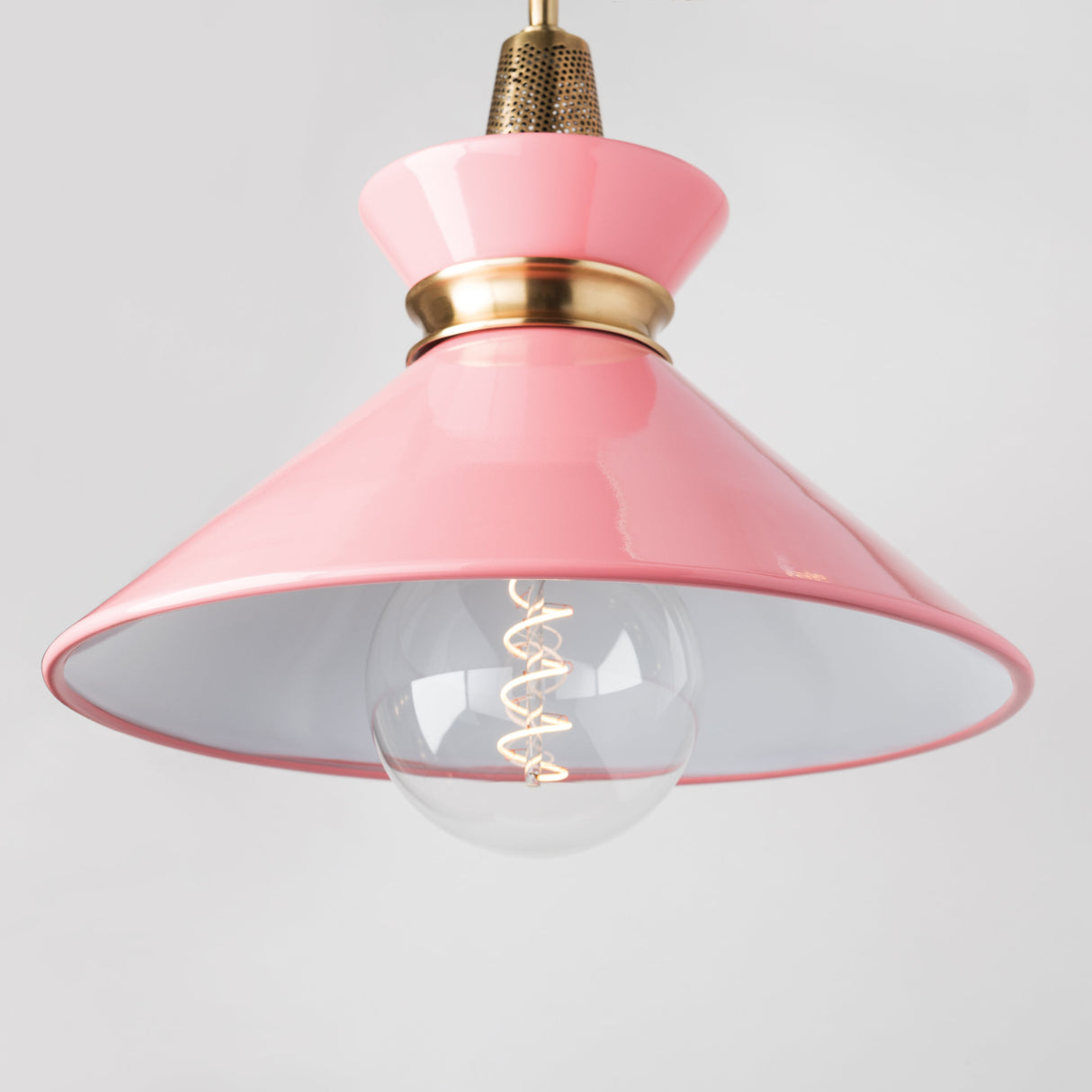 Pink pendant light with a clear bulb on a gray background