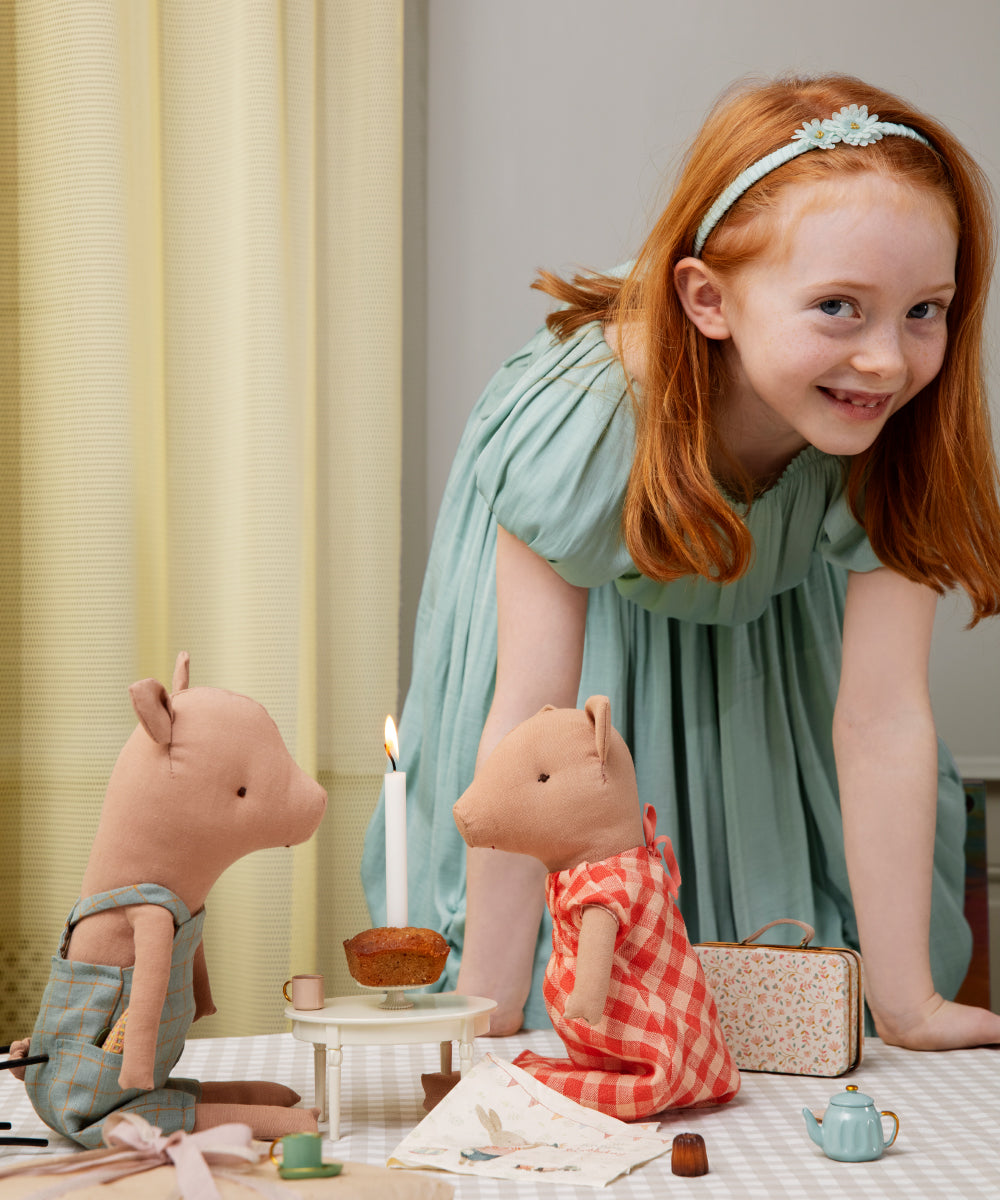 Young girl playing with toy pigs and other items on a table.