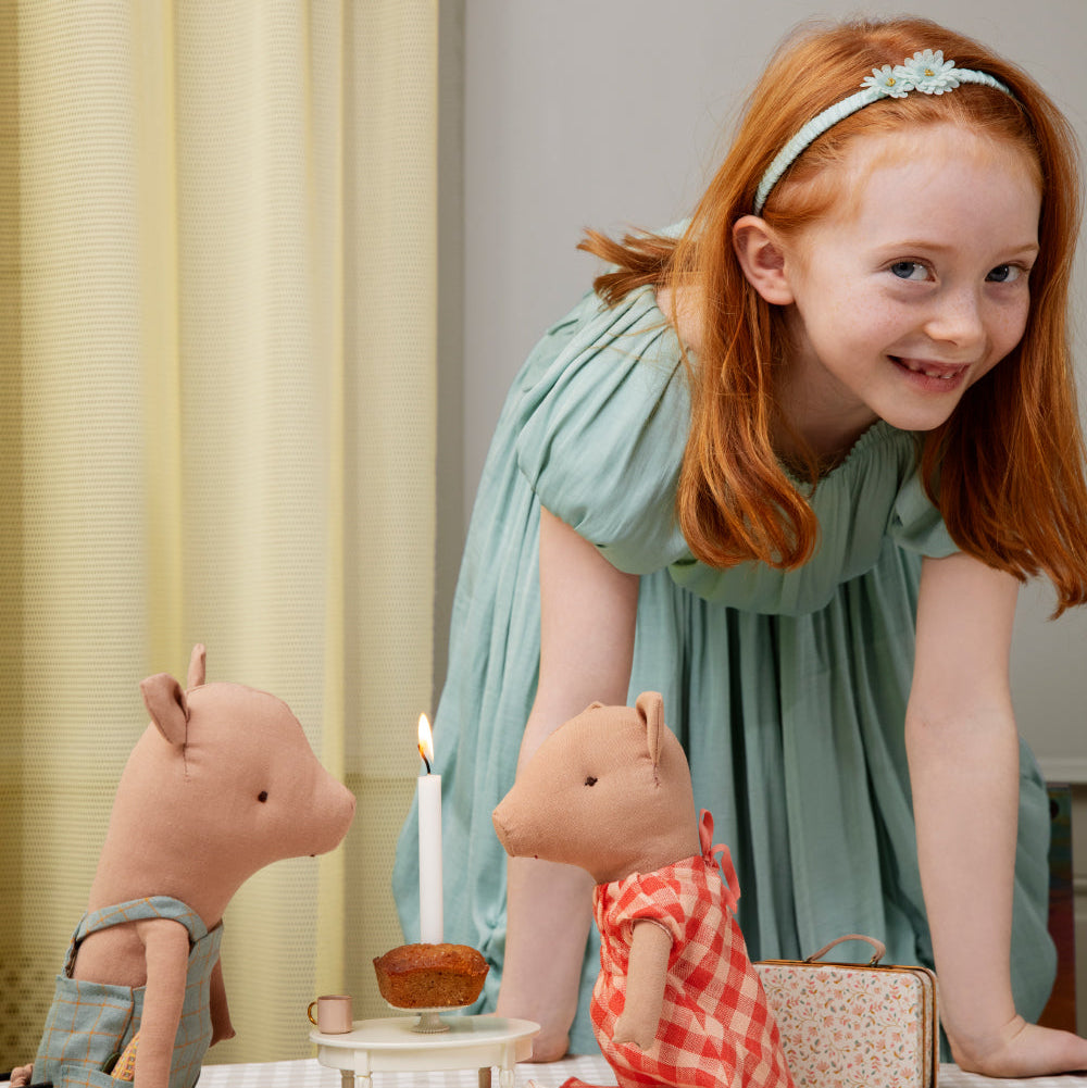 Young girl playing with toy pigs and other items on a table.