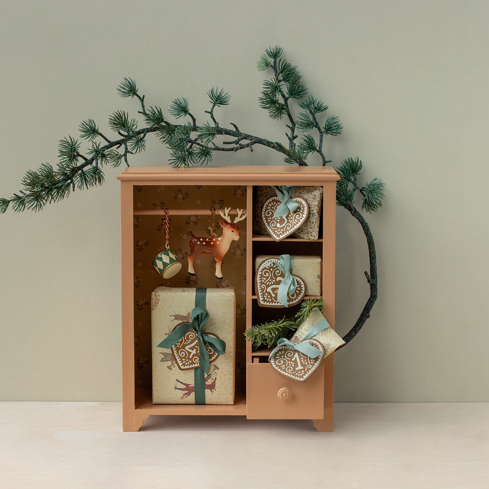 Wooden cabinet with decorative items and Christmas decorations on a light background