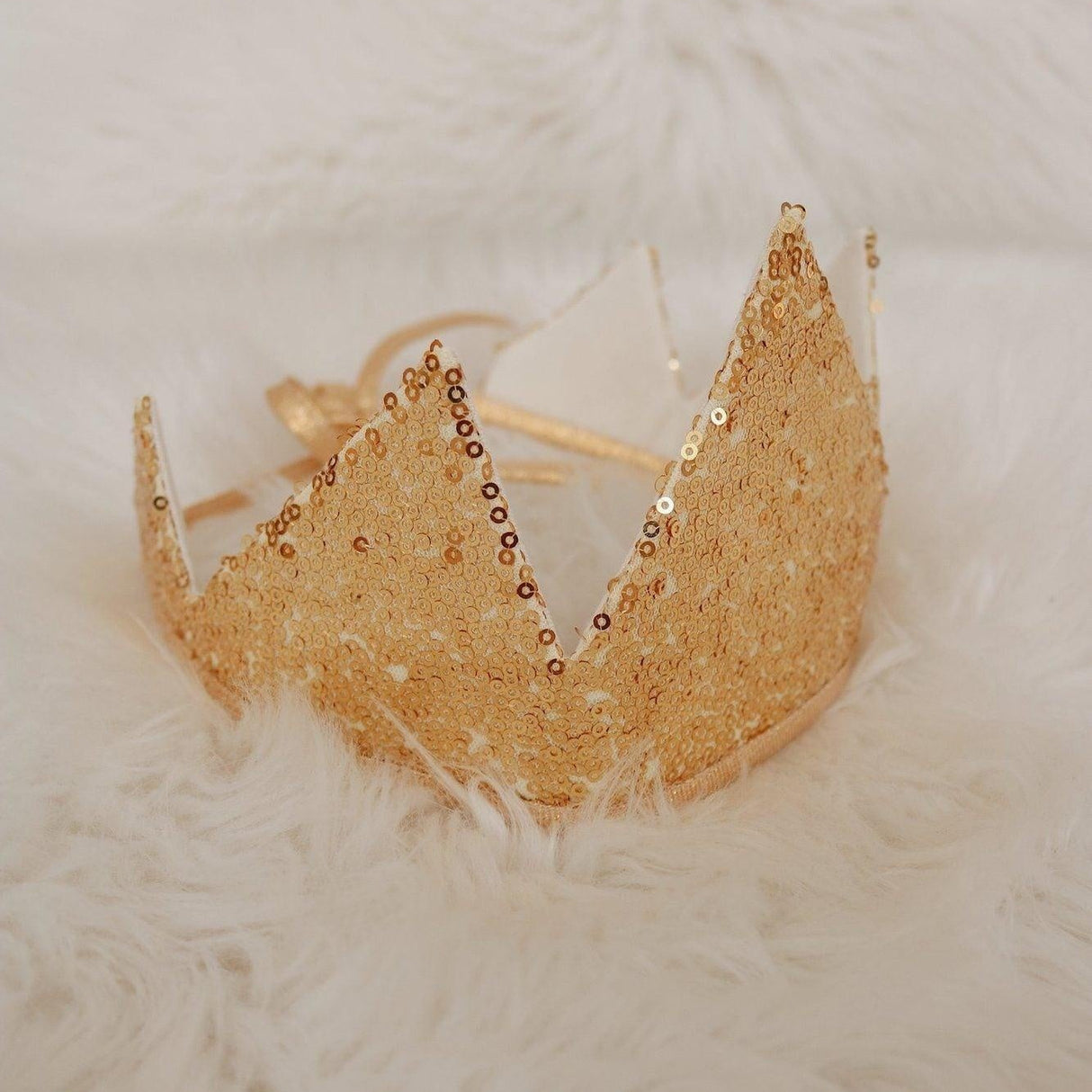 Gold tiara with beaded details on a textured white surface
