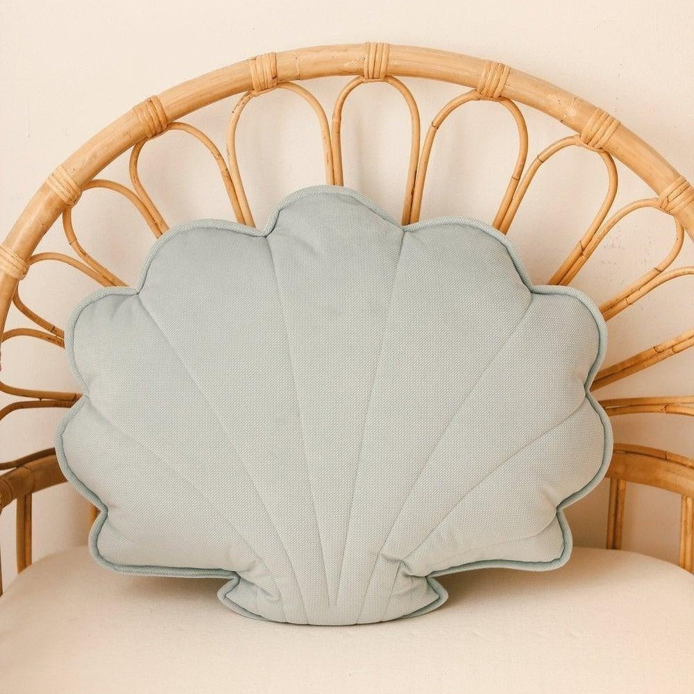 Shell-shaped pillow on a wicker chair with a beige background