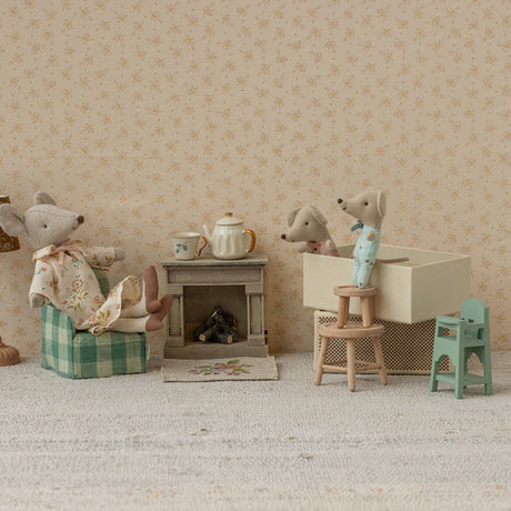 Miniature diorama with toy mice and furniture against a patterned wall.