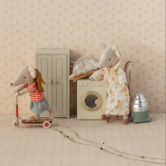 Two toy mice in a room with a washing machine and other items.