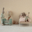Miniature room with toy rabbits and furniture against a patterned wall.