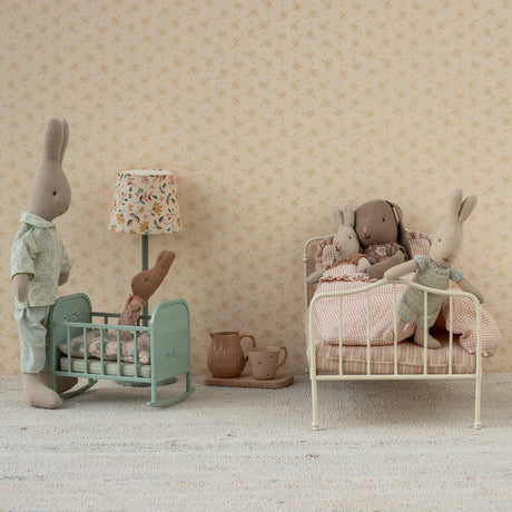 Miniature room with toy rabbits and furniture against a patterned wall.