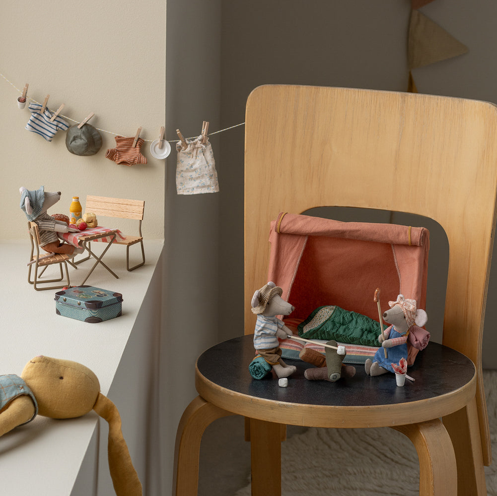 Wooden chair with a small toy setup on a carpeted floor in a room with toys and furniture.