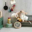 Toy rabbit lying on a bench in a kitchen setting with various items around