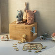 Wicker toy box with stuffed animals and toys on a light gray floor against a beige wall.