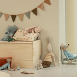 Children's room with wooden toy box, plush toys, and decorative elements.