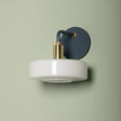Wall-mounted light fixture with white base and blue shade on a beige background