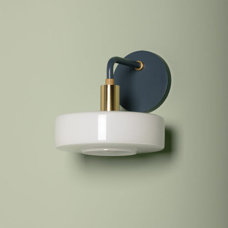 Wall-mounted light fixture with white base and blue shade on a beige background