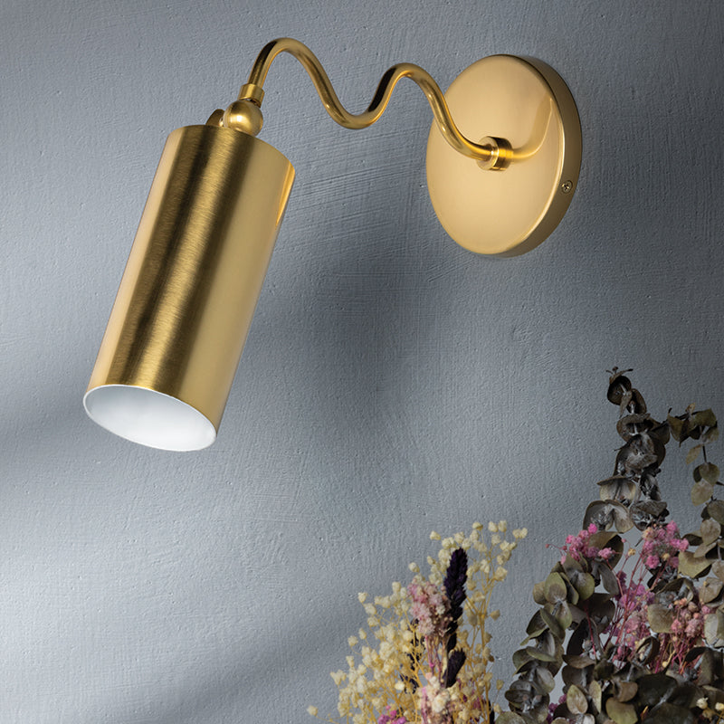 Gold wall-mounted lamp on a gray wall with dried flowers below.