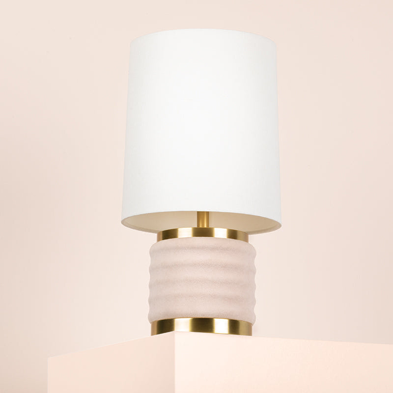 Wall-mounted lamp with white shade and gold base on a beige background