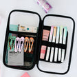 Open pencil case with stationery items including markers and hair clips on a white background
