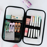Open pencil case with stationery items including markers and hair clips on a white background