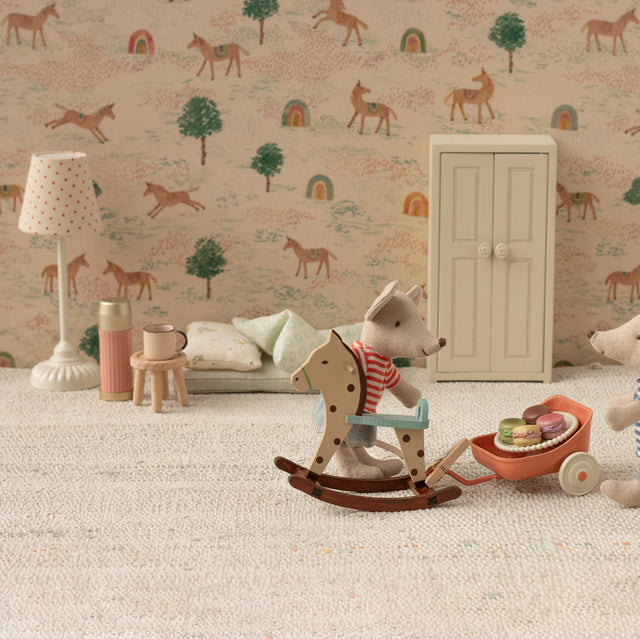 Children's room with toys and a patterned wall featuring animals and trees.