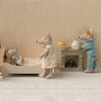 Miniature scene with toy mice in a room setting, including a bed, table, and lamp.