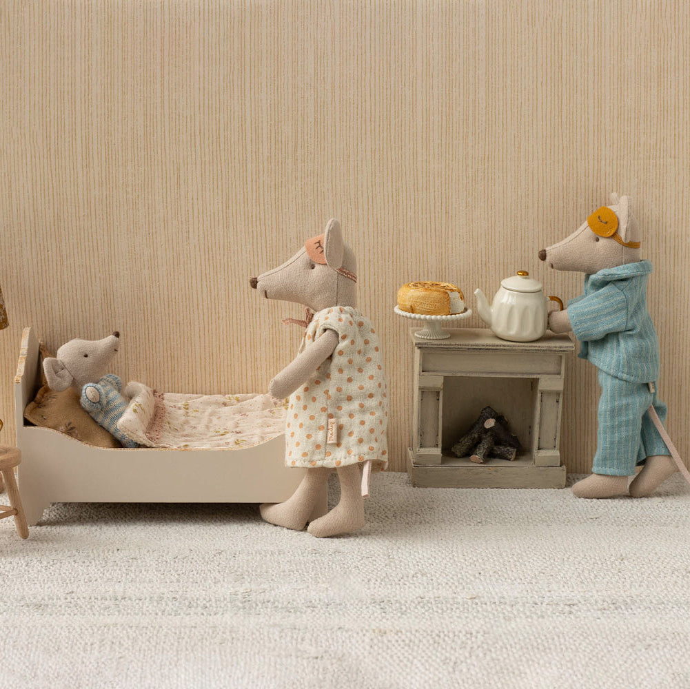 Miniature scene with toy mice in a room setting, including a bed, table, and lamp.