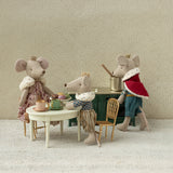 Four toy mice with human-like clothing and accessories in a room setting.