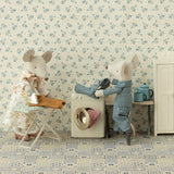 Two teddy bears in a room with floral wallpaper and a washing machine.