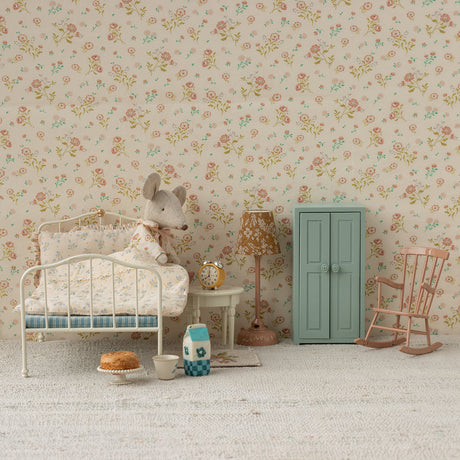 Miniature bedroom setup with floral wallpaper, dollhouse furniture, and decorative items.