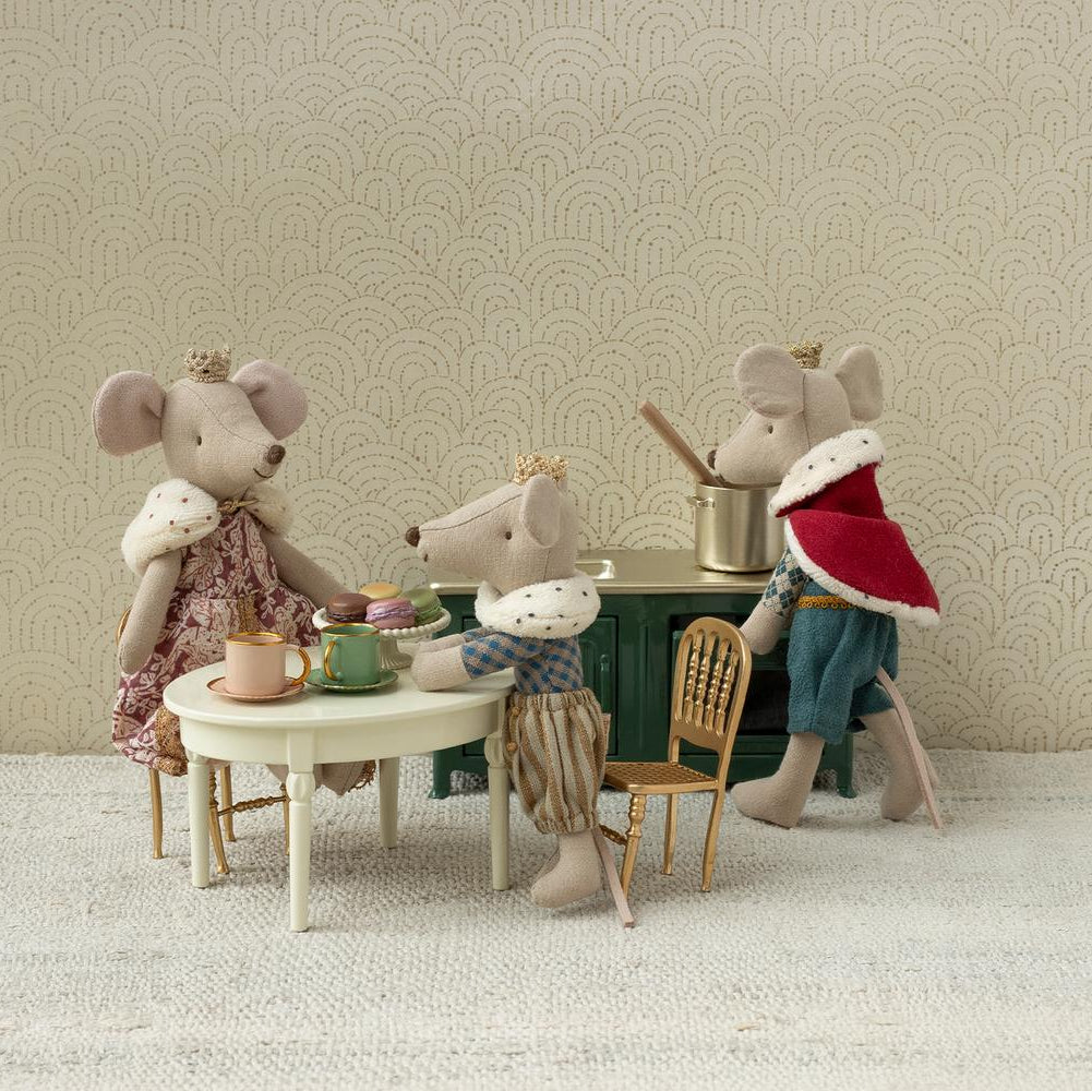 Miniature mouse figures in a tea party scene with a decorative wall background.