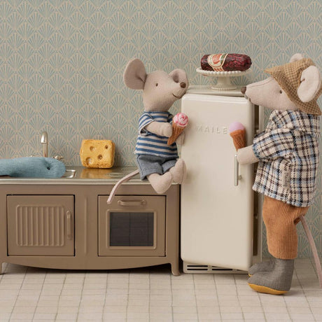 Two toy mice in a kitchen setting with a refrigerator and sink.