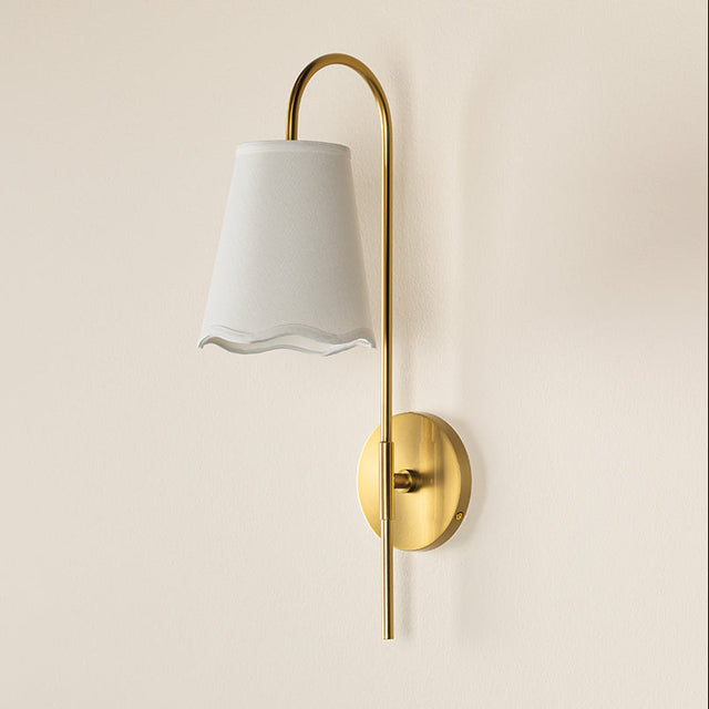 Wall-mounted lamp with white shade and gold fixture on a beige wall