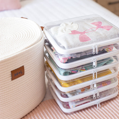 Stack of clear plastic storage containers with colorful lids on a bed.