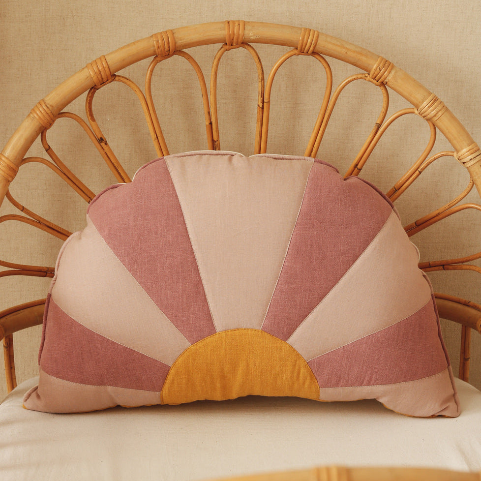 Decorative pillow with a sunset pattern on a wicker chair.