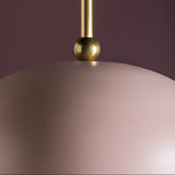 Close-up of a gold pendant on a pinkish surface with a dark purple background