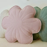 Floral-shaped pink cushion on a bed with decorative pillows and a flower banner in the background.