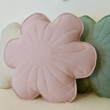 Floral-shaped pink cushion on a bed with decorative pillows and a flower banner in the background.