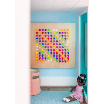 A child sitting on the floor looking at a wall-mounted LiteZilla Mini light grid sensory display with colorful illuminated pins.