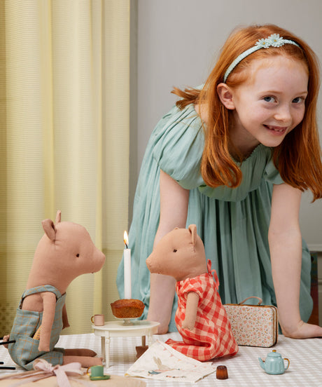 Young girl playing with toy pigs and other items on a table.