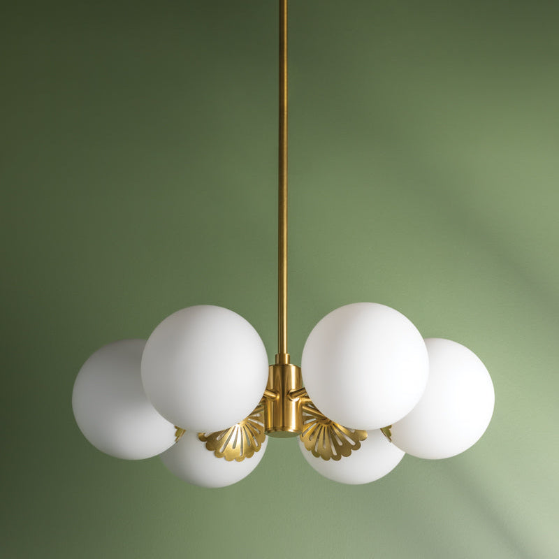 Chandelier with white glass bulbs and gold fixture on a green background