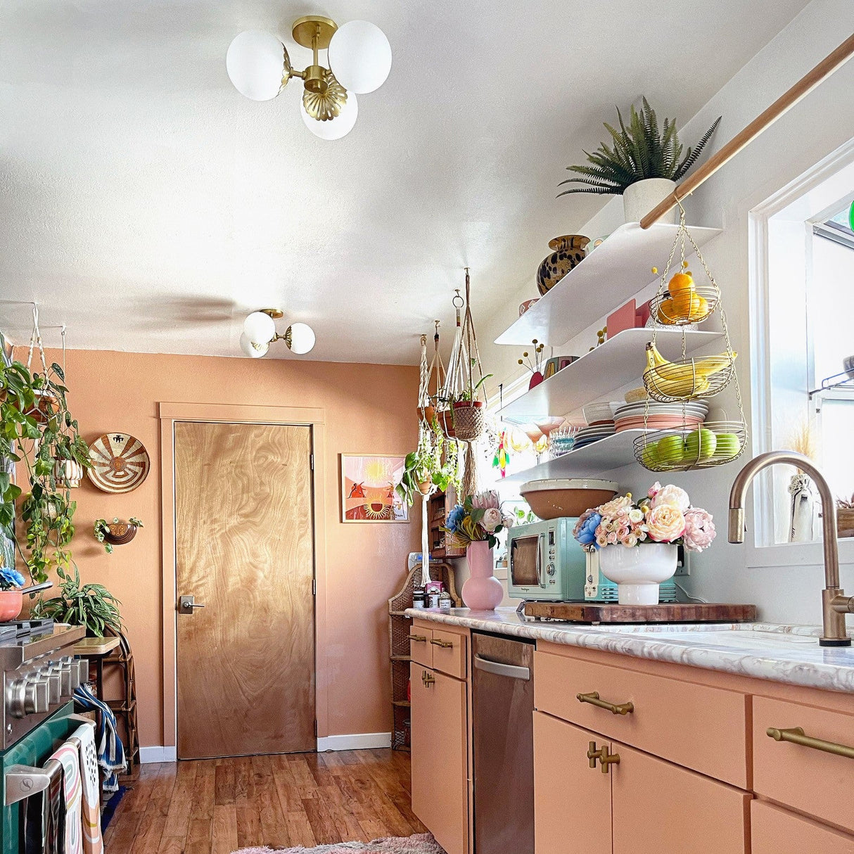 Modern kitchen with peach-colored cabinets, wooden floor, and decorative elements.
