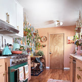 Kitchen with green oven, pink cabinets, and a Christmas tree.
