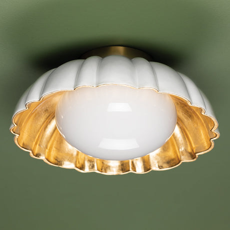 Decorative ceiling light fixture with white glass shade and gold metal trim on a green background