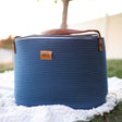 Blue woven basket with leather handle on a white blanket outdoors